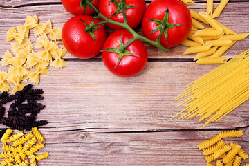 Bunch of raw spaghetti with a truss of tomatoes in a rustic scene