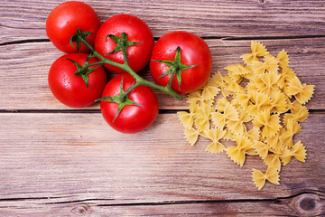 Bunch of raw spaghetti with a truss of tomatoes in a rustic scene