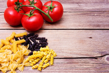 Bunch of raw spaghetti with a truss of tomatoes in a rustic scene