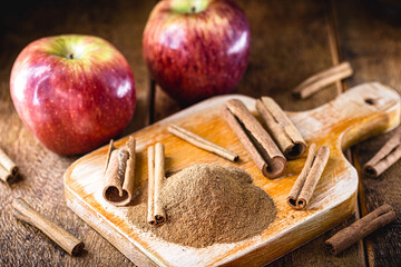 powdered, ground and peeled cinnamon. Cinnamon in a rustic kitchen, with red apples in the...