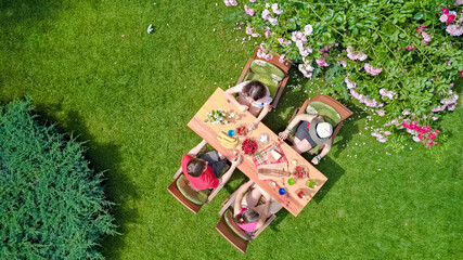 Family and friends eating together outdoors on summer garden party. Aerial view from above. Leisure, holidays and picnic concept
