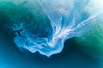 Leachate flowing off tidal mud flats near an anchored yacht.