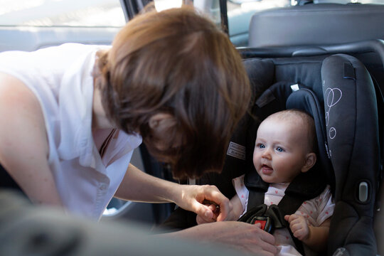 Mother Buckling In Her Baby Sitting In Rear-facing Car Seat