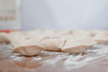 Sculpt dumplings. Dumplings with minced meat sculpts cook in the kitchen. Dumplings on the table sprinkled with flour.