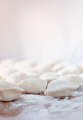 Sculpt dumplings. Dumplings with minced meat sculpts cook in the kitchen. Dumplings on the table sprinkled with flour.
