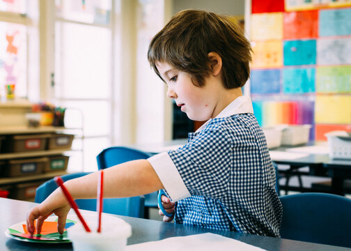 Little girl cutting & pasting in the classroom
