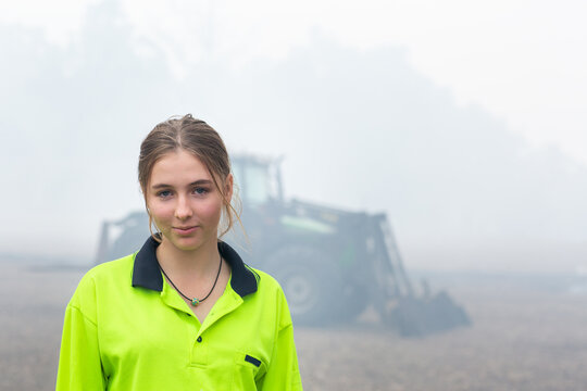 Young woman wearing hi-vis in front of tractor