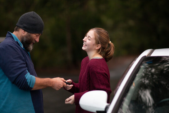 Father Handing Car Keys To Teenaged Daughter