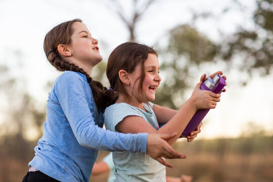 Siblings playing with water bottle outdoors