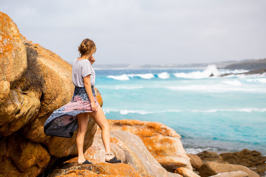 Young woman standing on rocks looking out to sea