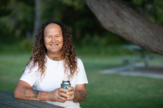 smiling middle-aged man holding drink outdoors in park