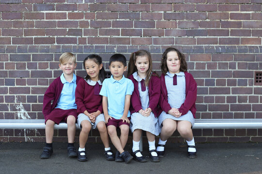 Group of kids sitting together on a school bench outside
