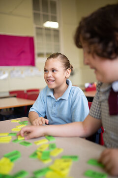 Primary school students sitting and working with coloured word tiles
