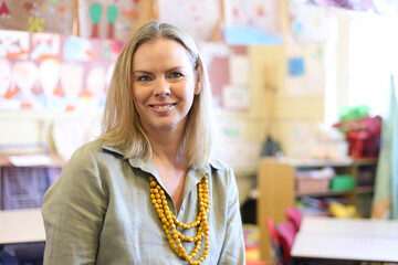 Female teacher in classroom, smiling at the camera