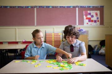 Two primary school girl students collaborating with coloured word tiles