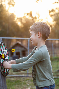 Young boy pulling throwing darts of game board
