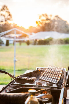 Rissoles cooking on a BBQ in the backyard at sunset