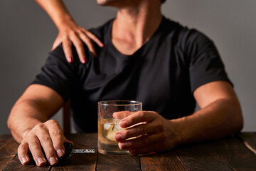A man's hand trying to stop her partner from drinking at a bar. Concept of alcoholism and drinking addiction.
