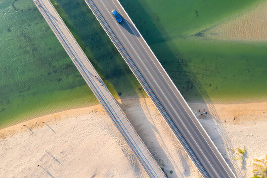 Aerial view of two bridges crossing a coastal river and sandy beach