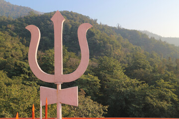 The symbol of Lord Shiva is the trishula trident against the backdrop of mountains in Rishikesh,...