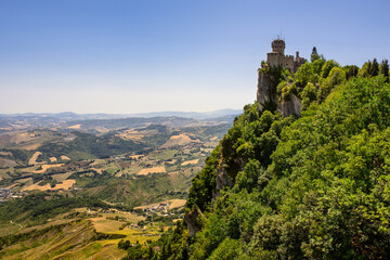Fototapeta na wymiar The old fortress stands on top of a mountain. View of the fortress and fields in the Republic of San Marino
