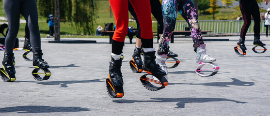 The company of young and attractive girls is engaged in aerobics in the fresh air. Healthy lifestyle. Sports shoes close-up