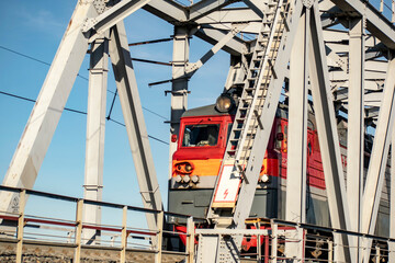 Locomotive passes through the metal bridge.