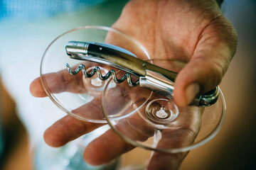 Close-up shot of man's hand holding wine glasses and wine key