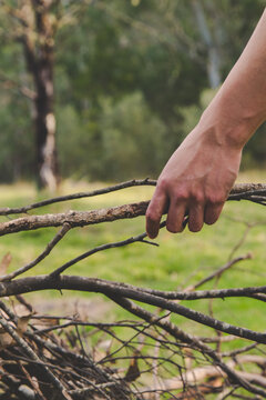 Man placing branch on camp fire kindling pile in outback