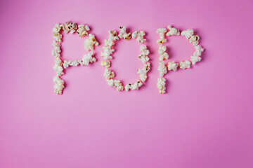 Word POP written with popcorn on pink background, copy space