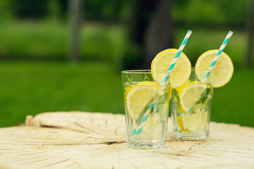 Lemonade with lemon and mint in glass on wooden background. Refreshing summer drink. 