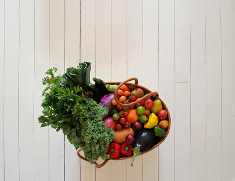Market basket with fruit and vegetables on white floorboards