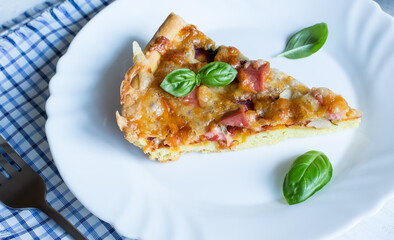 A slice of delicious and crispy pizza with olives and sausages on a light background with a blue napkin.