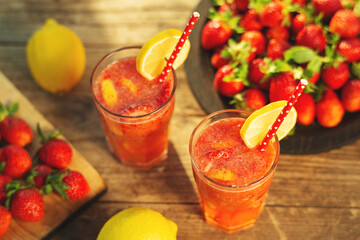 Strawberry lemonade with lemon and strawberries in glass on wooden background. Refreshing summer drink. Drink making ingredients for lemonade. Top view.