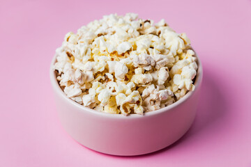 Close-up of a pink bowl of popcorn on pink background, top view