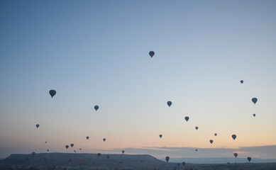 Hot air balloons at sunrise flying in the sky along valleys at Cappadocia of Goreme, Turkey 