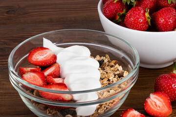 bowl of oat granola with yogurt, fresh strawberry on wooden background for healthy breakfast with copy space.