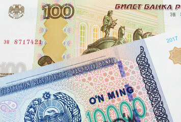 A macro image of a Russian one hundred ruble note paired up with a blue, white and green ten thousand som note from Uzbekistan.  Shot close up in macro.