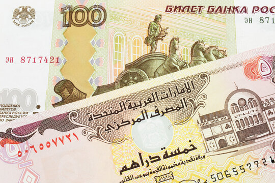 A macro image of a Russian one hundred ruble note paired up with a colorful five dinar bank note from the United Arab Emirates.  Shot close up in macro.