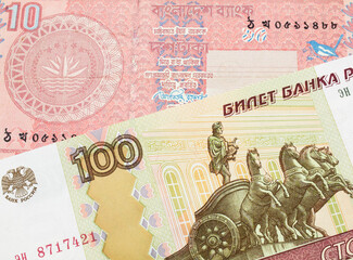 A macro image of a Russian one hundred ruble note paired up with a pink ten taka bank note from Bangladesh.  Shot close up in macro.
