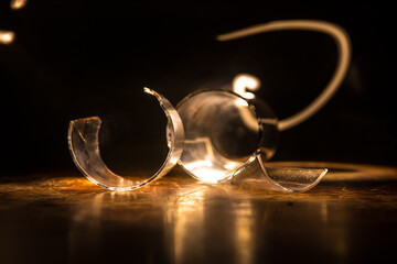Broken glasses on wooden table at dark toned background with fog. Selective focus