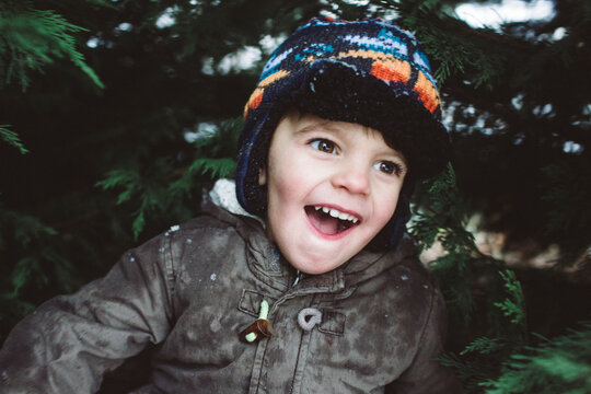 child playing in snow around evergreens