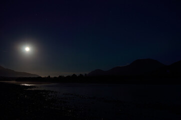 Fototapeta na wymiar full moon river landscape at night surrounded by mountains