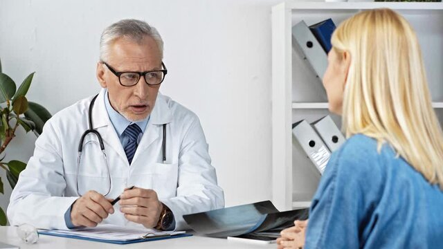 selective focus of mature doctor talking with patient near x-ray