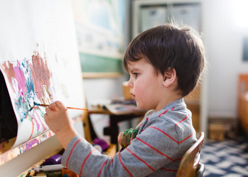 child paints at easel