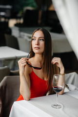 Beautiful young girl sits and drinks wine on the veranda of a beautiful house. Holiday.