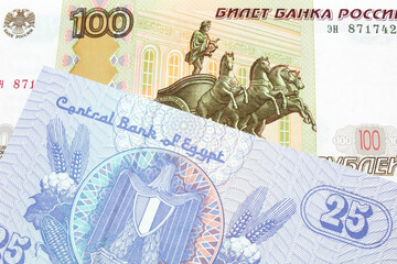 A macro image of a Russian one hundred ruble note paired up with a blue twenty five piastre bank note from Egypt.  Shot close up in macro.