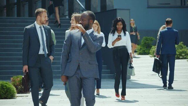 Happy energetic black businessman dancing on streetin sunny weather. Successful entrepreneur celebrating hsi business triump. Corporate people. Office crowd.