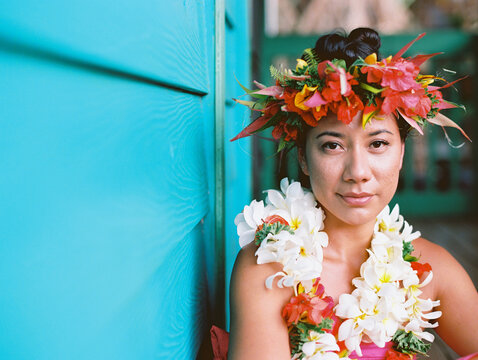 tahitian woman at turquoise plantation house in hawaii with surfboard and shower and floral crown