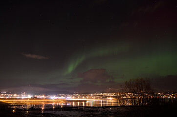 vivid strong aurora borealis over the arctic city of tromsoe in late autumn